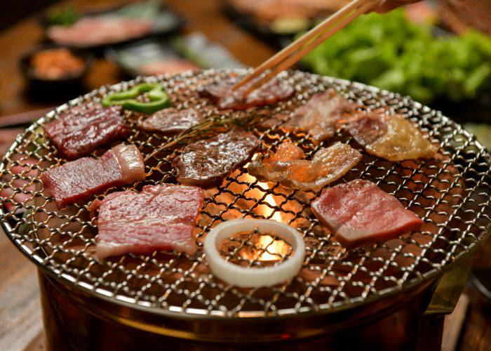 A variety of high-quality wagyu beef slices being grilled at a yakiniku restaurant.